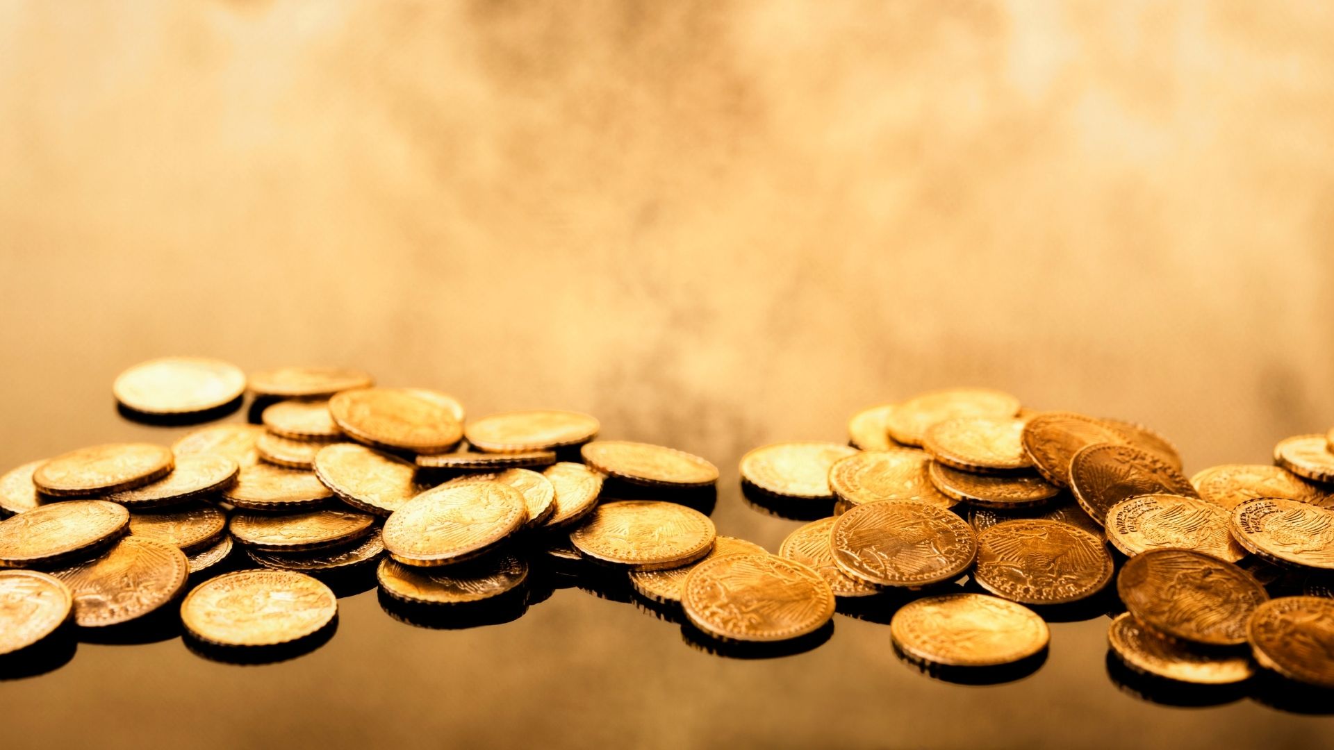 Piles of shiny gold coins on reflective surface.